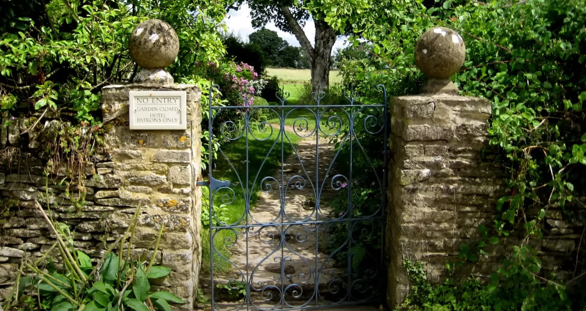 Classic garden entrance design with custom ironwork and natural stone Traditional garden entrance with ornate iron gate and stone pillars