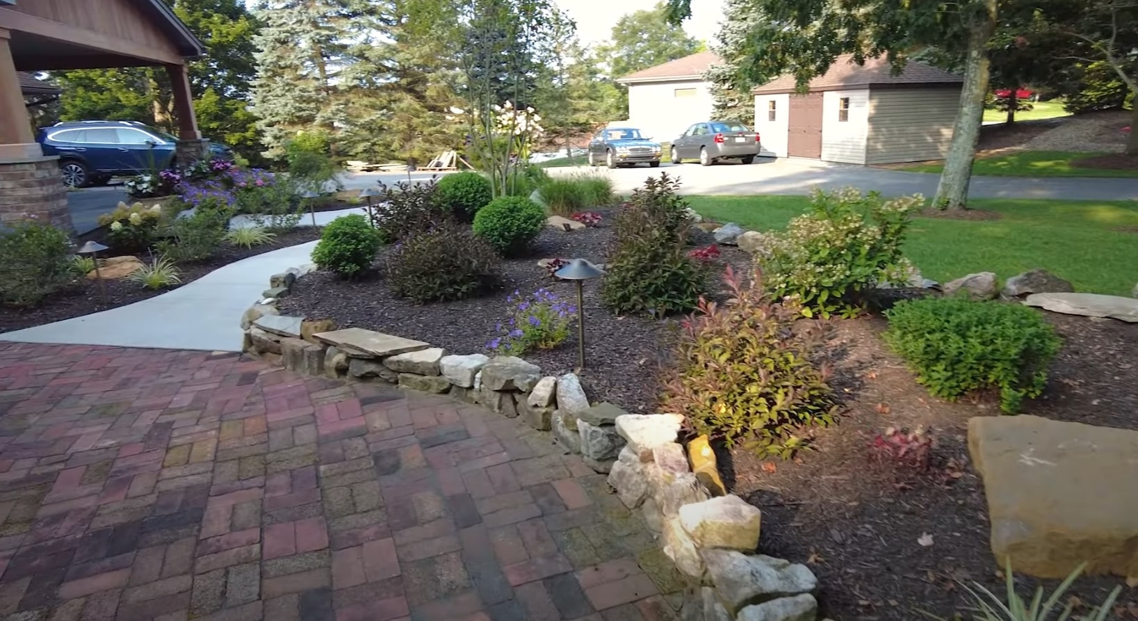 Complete front yard transformation with stone accents and seasonal flowers Residential front yard landscaping with natural stone features and colorful plantings